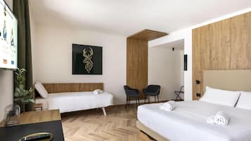 A hotel room with two single beds, a desk with a remote control, a wooden accent wall, and a black wall art piece.
