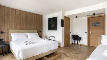 Une chambre d’hôtel moderne avec un grand lit, un mur décoratif en bois, une chaise noire et une porte avec une pancarte.
