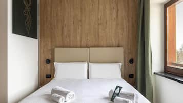 Un lit bien fait, avec deux oreillers, une tête de lit en bois et une fenêtre avec des rideaux.