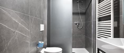 A modern bathroom with a shower, toilet, and sink.