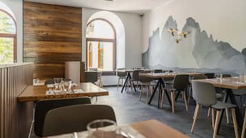 Ein Restaurant mit Holzwandverkleidung, einer Wandmalerei von Bergen und Blick durch große Fenster.