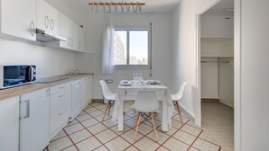 A modern kitchen with white cabinets, a microwave, and a dining table with chairs. - Fauriel Aimé - Prestations haut de gamme - St Etienne (Saint Etienne)