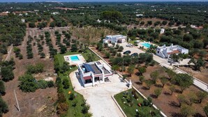 Vue aérienne d’un quartier résidentiel comprenant plusieurs maisons, une piscine et une pelouse bien entretenue.