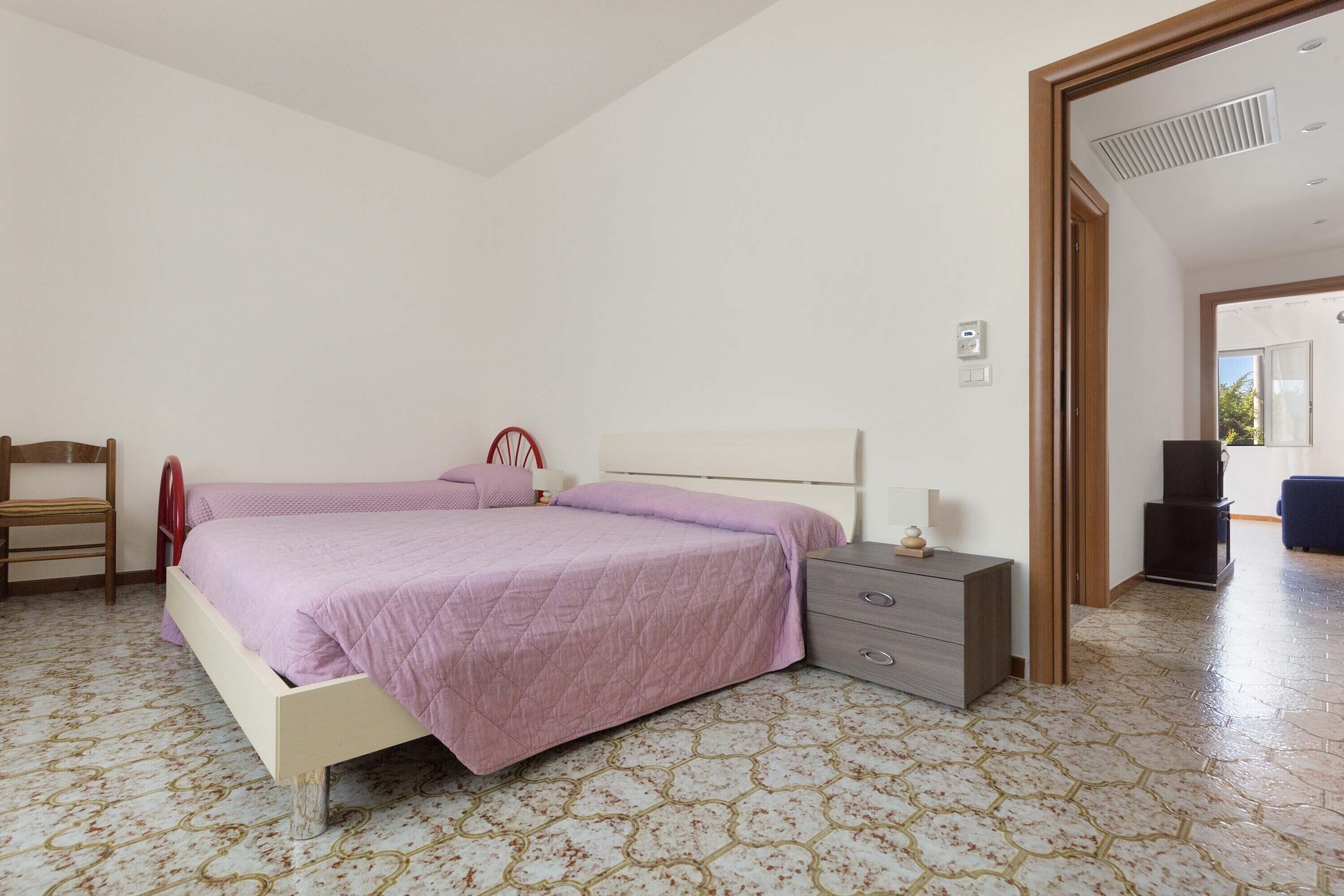 A bedroom with two beds, a chair, a nightstand, and a wardrobe.