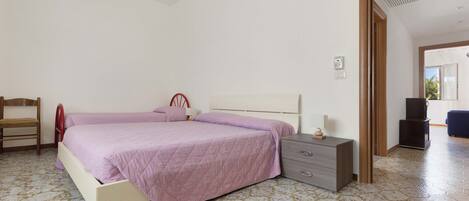 A bedroom with two beds, a chair, a nightstand, and a wardrobe.