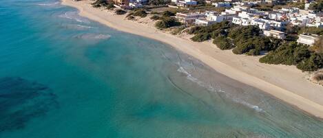 An aerial view of a coastal town with a beach and residential buildings.
