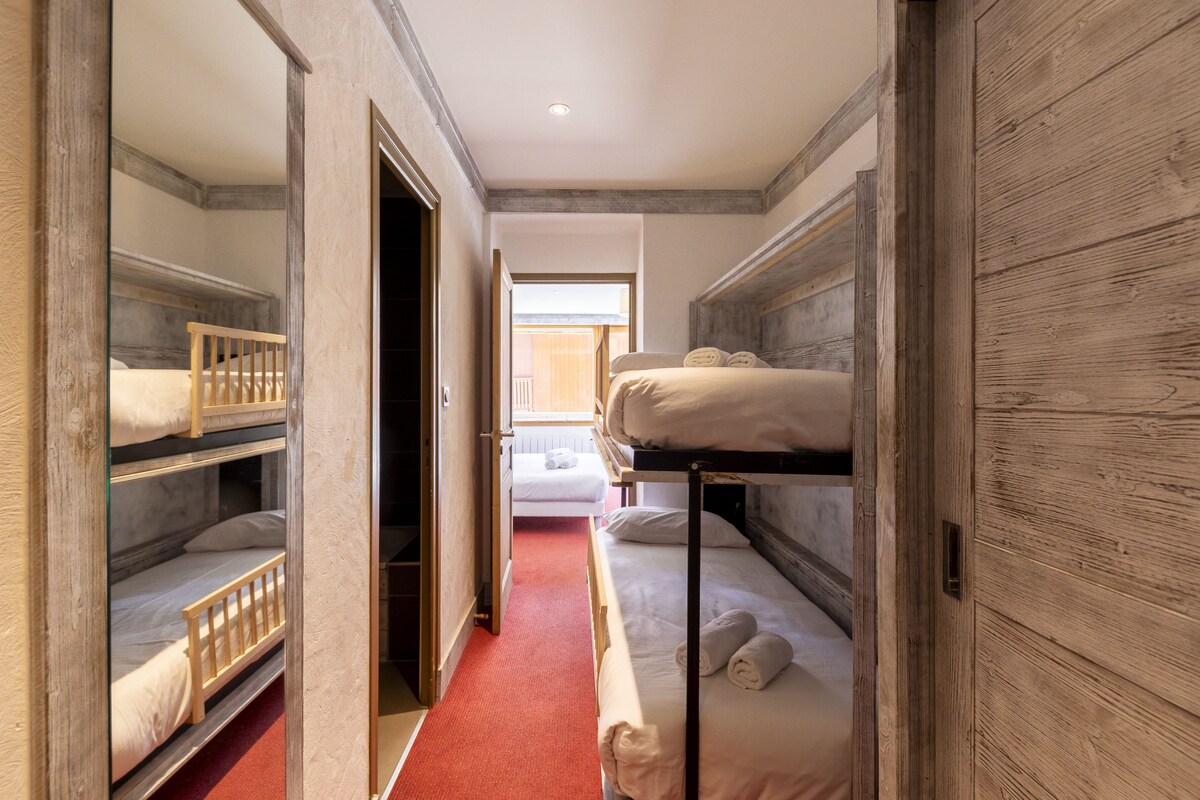 A room with bunk beds, a red carpet, and a wooden wall.