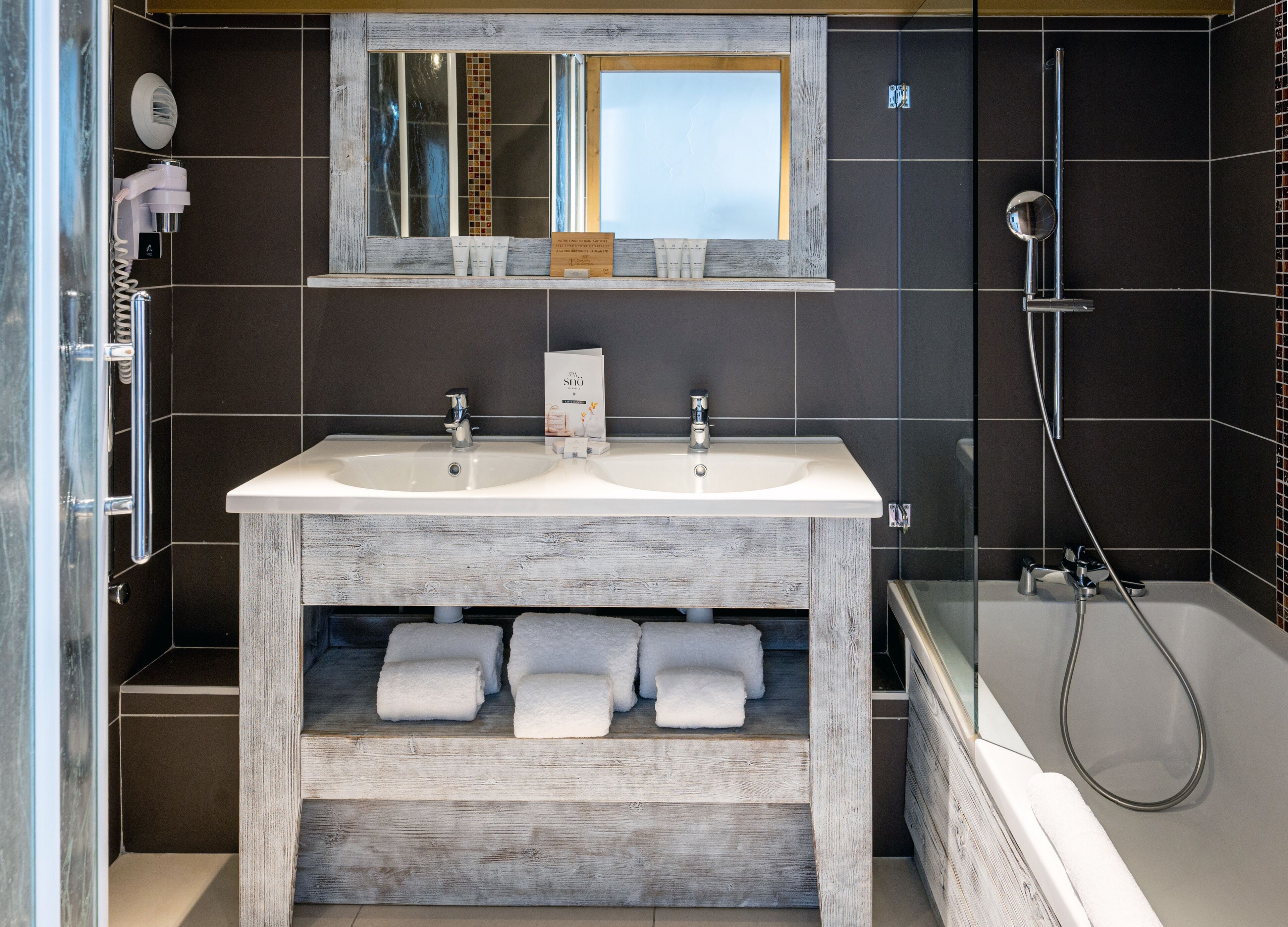 Un baño moderno con dos lavamanos, un espejo y una ducha.