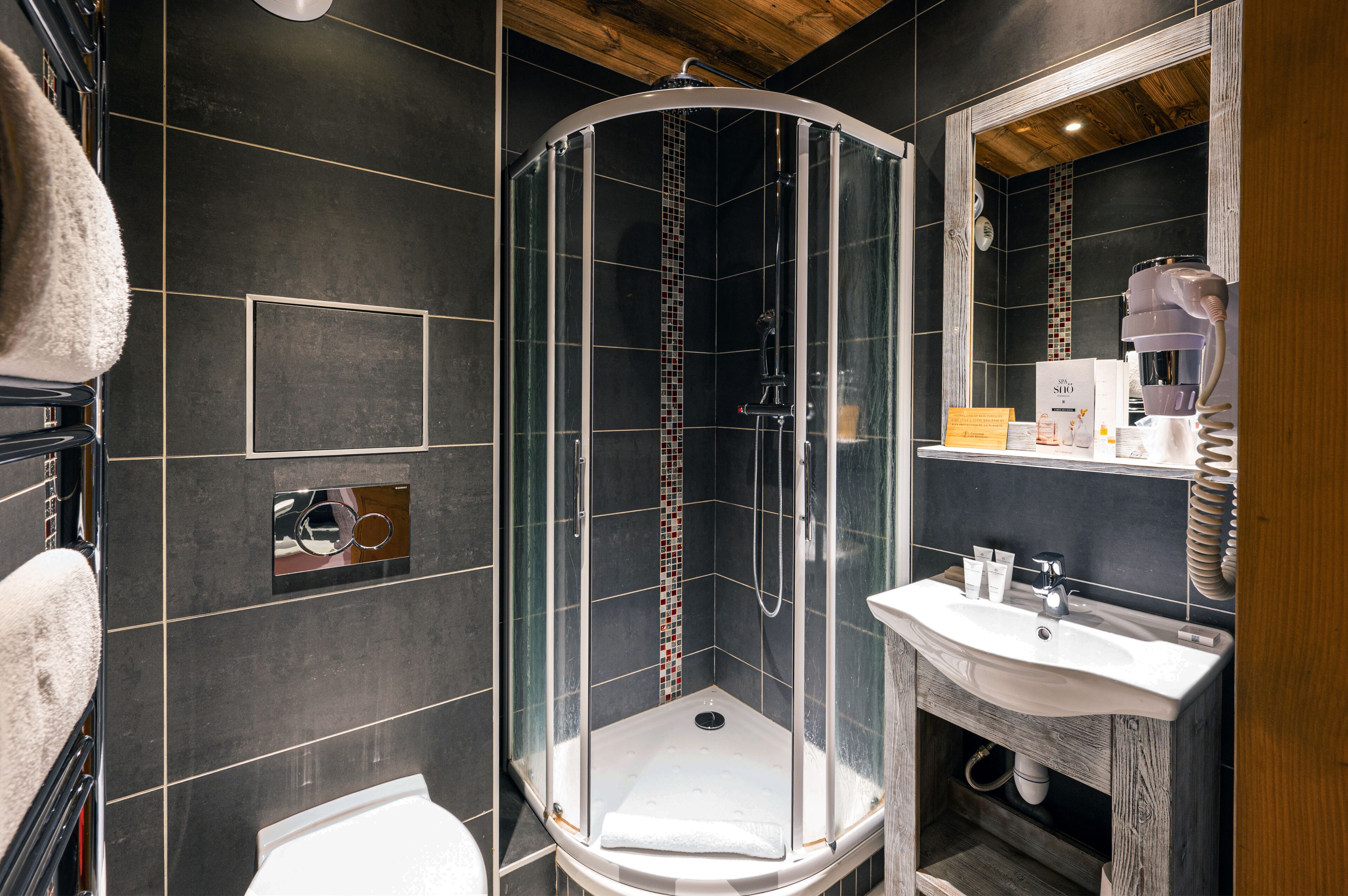 A modern bathroom with a glass-enclosed shower, a white sink, and a wooden vanity.