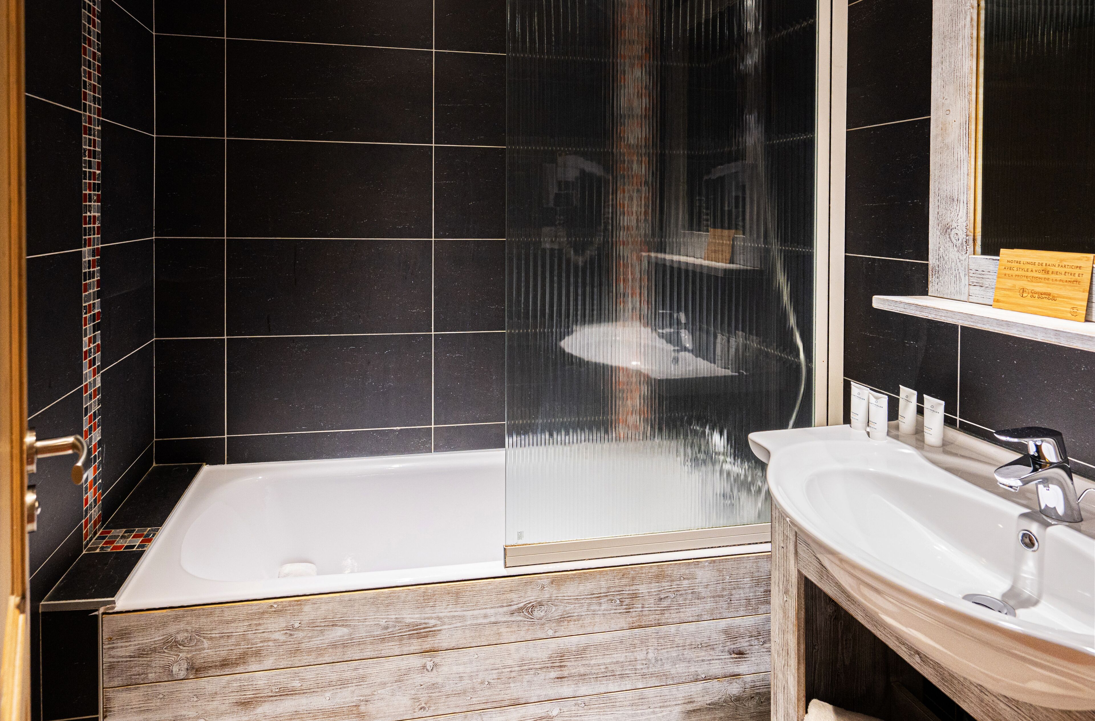 A modern bathroom with a bathtub, a wooden vanity, and a glass shower enclosure.