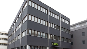 A modern hotel building with a flat facade, multiple windows, and a sign indicating it is a hotel.