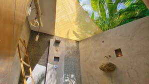 Un bany modern amb una paret de pedra, una escala de fusta i una petita roca decorativa.