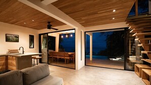 Un interior modern amb cuina, zona de menjador i un gran finestral corredís que dona a un espai exterior.
