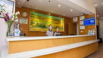 A reception desk with a clock, a digital display, and a painting on the wall.