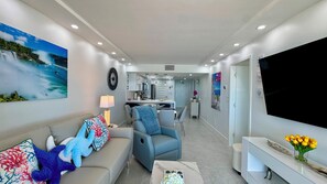A modern living room with a sofa, armchairs, a coffee table, and a TV. - Sea Winds 705: Completely Renovated Beach Front Condo! (Marco Island)