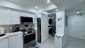 A modern kitchen with stainless steel appliances, a microwave, a coffee maker, and a dishwasher. - Sea Winds 705: Completely Renovated Beach Front Condo! (Marco Island)