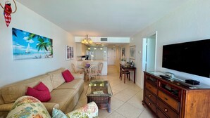 A living room with a sofa, TV, and a painting of a sailboat. - BLDG Construction Aug-Oct 2026; See Desc below! Sea Winds 705 (Marco Island)