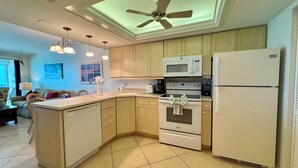 A kitchen with wooden cabinets, a microwave, a stove, and a refrigerator. - BLDG Construction Aug-Oct 2026; See Desc below! Sea Winds 705 (Marco Island)