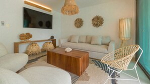 A modern living room with a sofa, coffee table, and wicker chair. - Amazing Beachfront Villa (San Miguel de Cozumel)