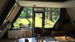 Une pièce avec une grande fenêtre, une table à manger, des chaises, une petite table avec une plante et un canapé.