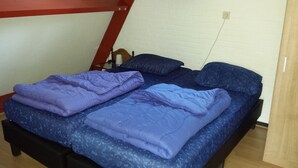 Un lit simple avec un matelas bleu et une literie violette.