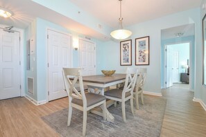 Un comedor con mesa y sillas de madera, paredes azul claro y un pasillo que conduce a otra habitación.