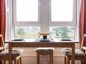A dining table set for two with a view of buildings through large windows. - ☆ Bright, 2 Bedroom West End Apartment ☆ (Dundee)