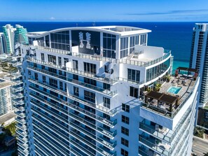 Un hôtel de grande hauteur doté de nombreux balcons, d’une piscine sur le toit et offrant une vue sur l’océan.