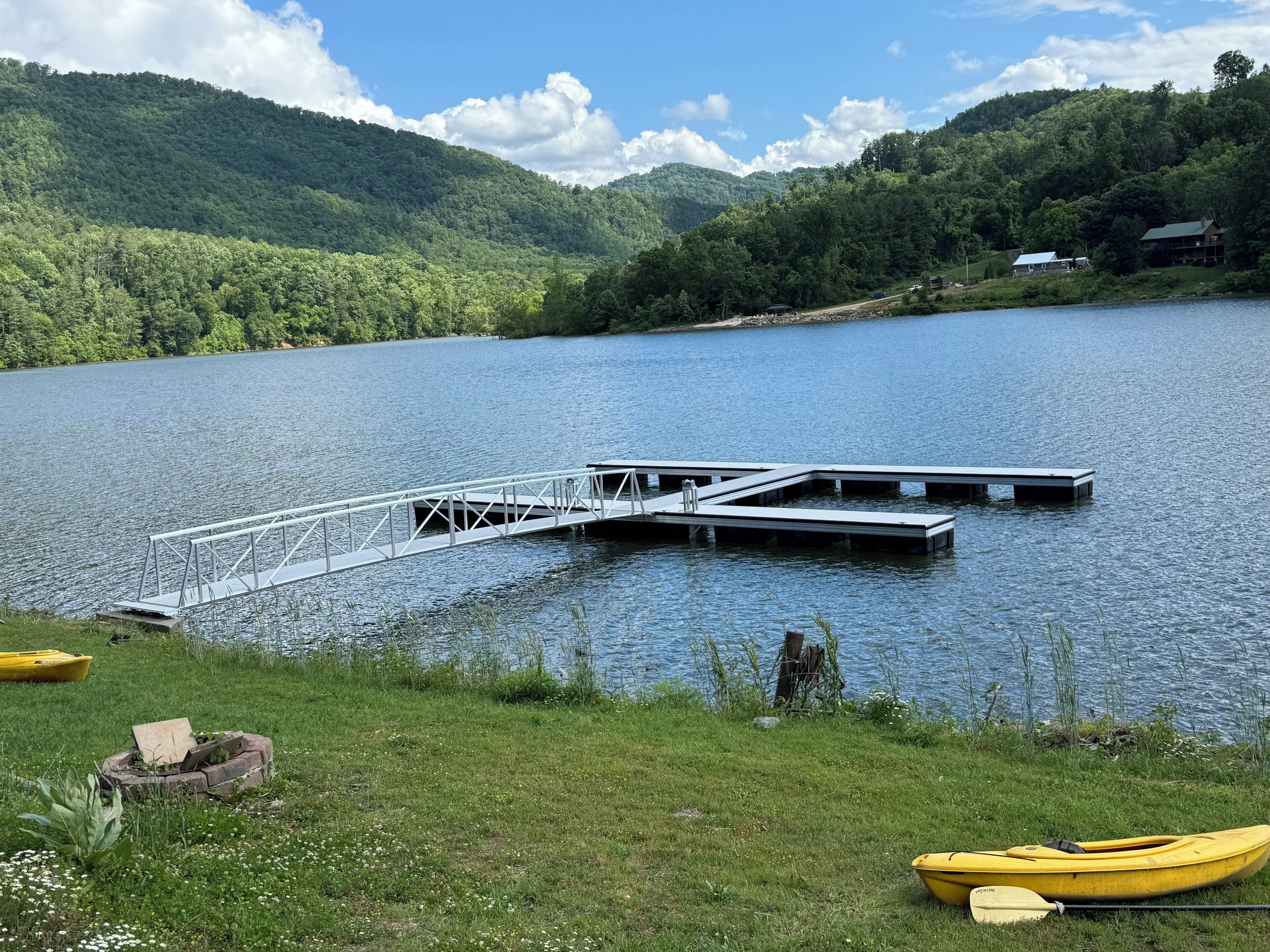 A lake with a dock and a yellow kayak.