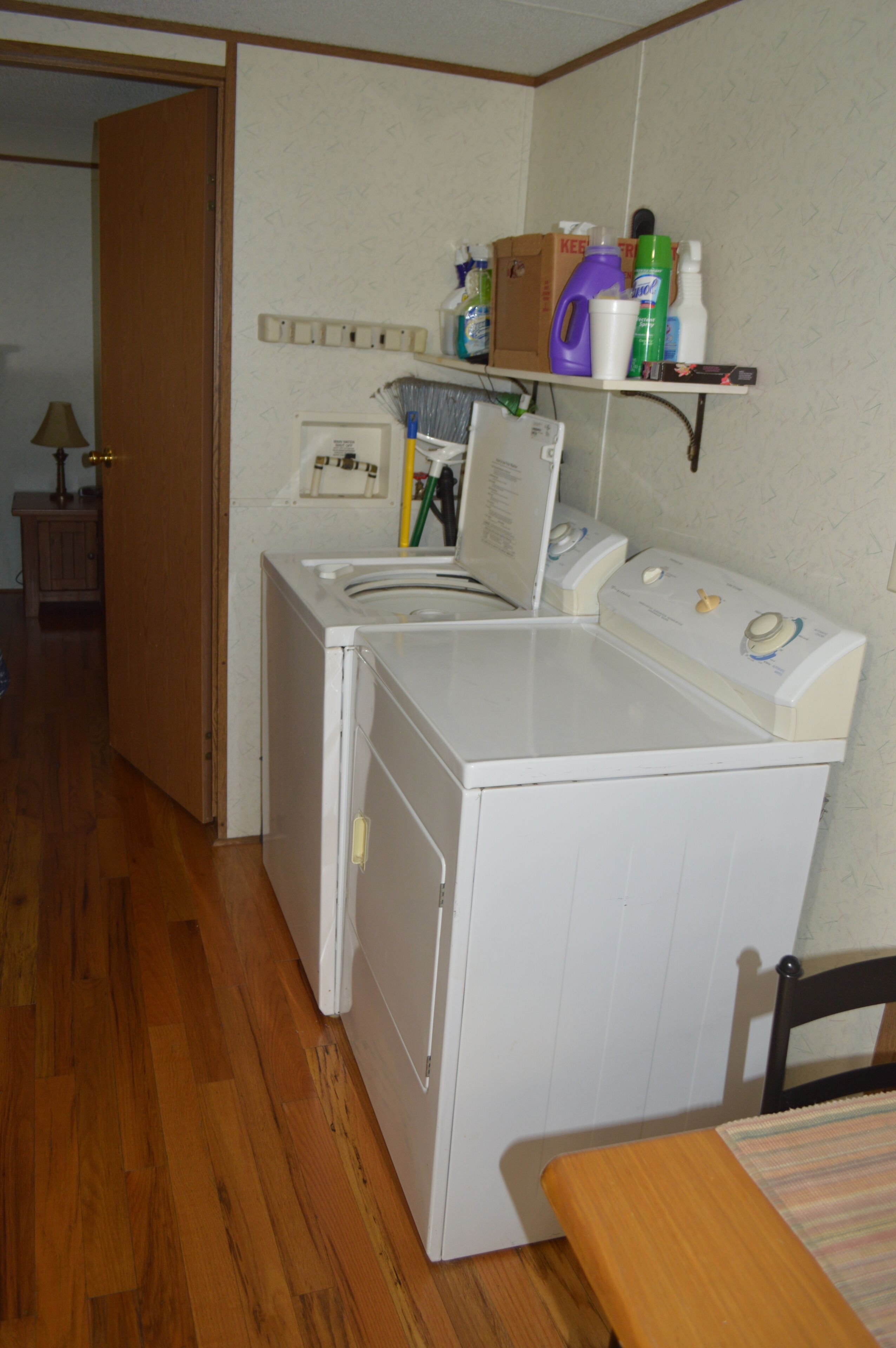 A laundry area with a washing machine, dryer, and a shelf with cleaning supplies.