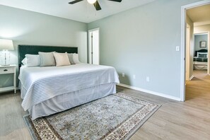 Un dormitorio con cama, mesita de noche y ventilador de techo.