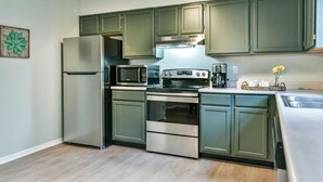 A compact kitchen with a refrigerator, microwave, stove, and oven. - Roomy 3 BR Condo Walkable to IU (Bloomington)
