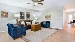 A living room with a sofa, a coffee table, a rug, and wall art. - Roomy 3 BR Condo Walkable to IU (Bloomington)
