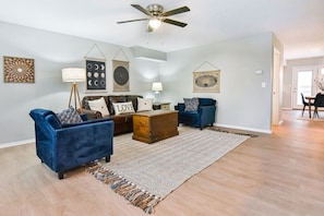 A living room with a sofa, a coffee table, a rug, and wall art.