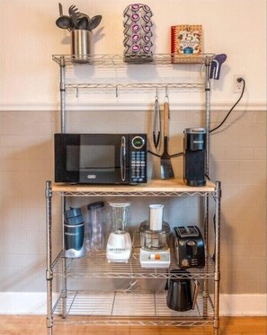 Fully equipped kitchen with microwave, coffee maker, blender, toaster, and utensils.