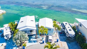 A coastal property with multiple RVs and a house, surrounded by clear blue waters and a small island in the distance. - ATLANTIS...Ocean Front Cottage Retreat! (Cudjoe Key)