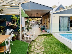 Relax in a spacious living area with a patio, featuring a hanging chair, cushioned bench, and pet-friendly amenities.