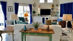 Una sala de estar con sofá, sillones, mesa de centro, televisor y objetos decorativos.