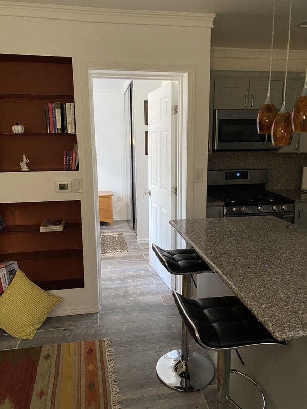 A modern kitchen with a granite countertop, stainless steel appliances, and a bar stool.