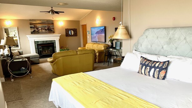 A hotel room with a large bed, a fireplace, a sofa, and a desk.