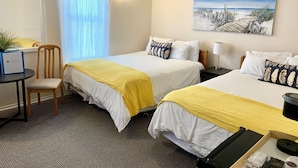 Ein Hotelzimmer mit zwei Betten, einem Schreibtisch, einem Stuhl, einem Gemälde und einer Lampe.