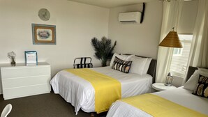 A hotel room with two beds, a white dresser, a plant, and a window with curtains. - 201 - Executive Rm Lake View- Balcony 2 DBL (Port Elgin)