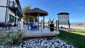 A beachside resort with a wooden deck, lounge chairs, a thatched gazebo, and a sign for Paradise Inn. - 201 - Executive Rm Lake View- Balcony 2 DBL (Port Elgin)
