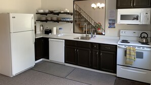 A modern kitchen with dark cabinets, a white refrigerator, a microwave, and a stove. - 202 - Executive Rm Lake View- Balcony 2 DBL (Port Elgin)