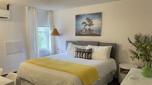 A neatly arranged hotel room with a large bed, a bedside table, a lamp, and a painting on the wall.