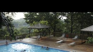 Una piscina con sillas de descanso y un pabellón.