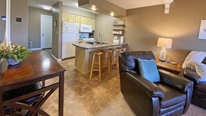 Una cocina moderna con una isla central, taburetes de madera, un sofá de cuero y una mesa de comedor.