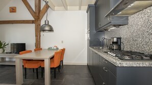 Una cuina moderna amb encimera de granat, fornel electrònic d'acer inoxidable i bigues de fusta.
