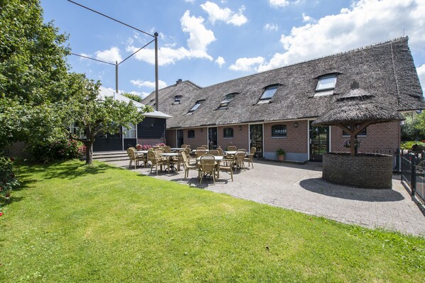 A building with a thatched roof, brick walls, and a patio with outdoor seating.