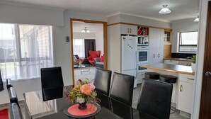 A compact living space with a dining area, kitchenette, and a view through a doorway.